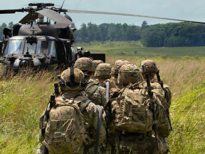 Soldiers preparing to be lifted off the ground on a rope during SPIES training