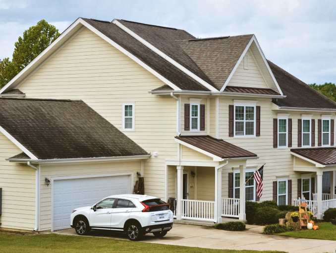 A yellow house with a SUV parked in the driveway