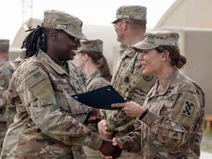 An Officer shaking hands and congratulating a Soldier at a graduation ceremony