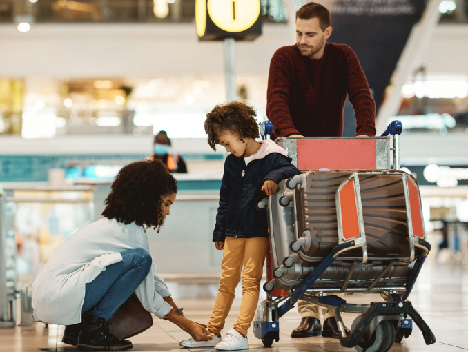 A mom tying her young child's shoes in an airport