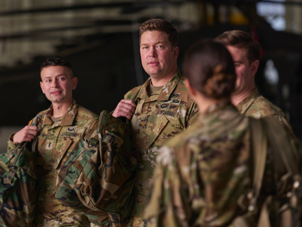 A group of Soldiers in combat uniform carrying camouflage bags