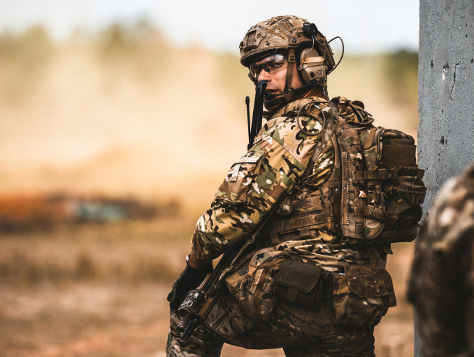 A kneeling Army Ranger looking over his shoulder during a live fire exercise