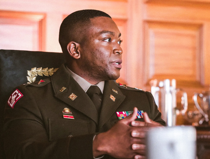 A uniformed Officer sitting at a desk with his hands clasped