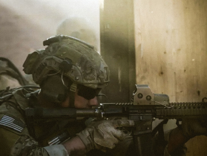 A male Soldier in combat gear aiming a rifle