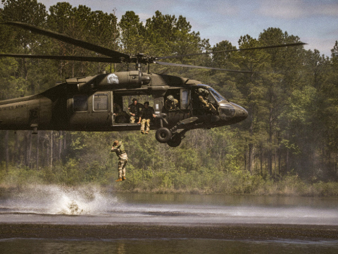 A Soldier jumps from a low flying helicopter into a lake