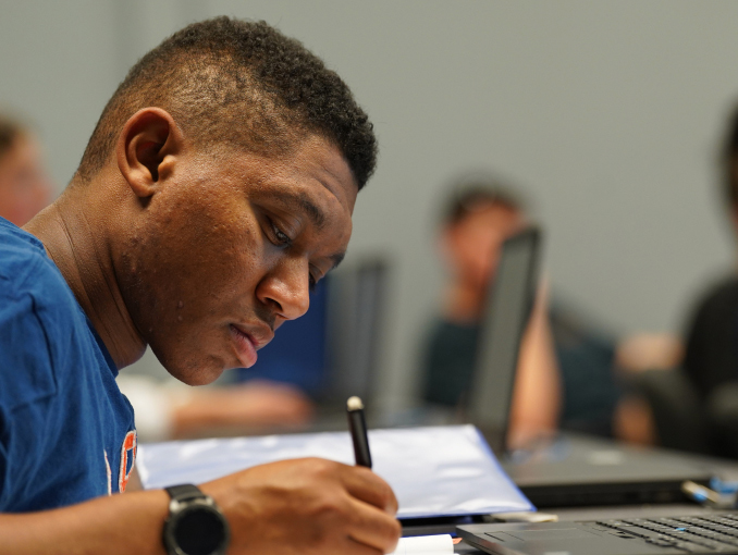 Male student taking notes in a classroom