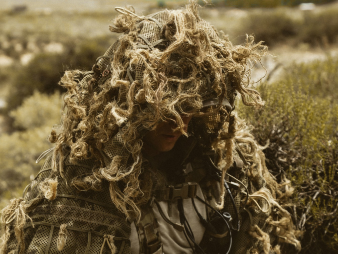 A U.S. Army Special Forces sniper prepares to set up over a watch position on a hill