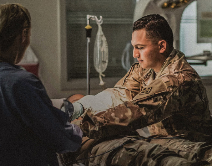 Army health care workers tending to a patient in an emergency room