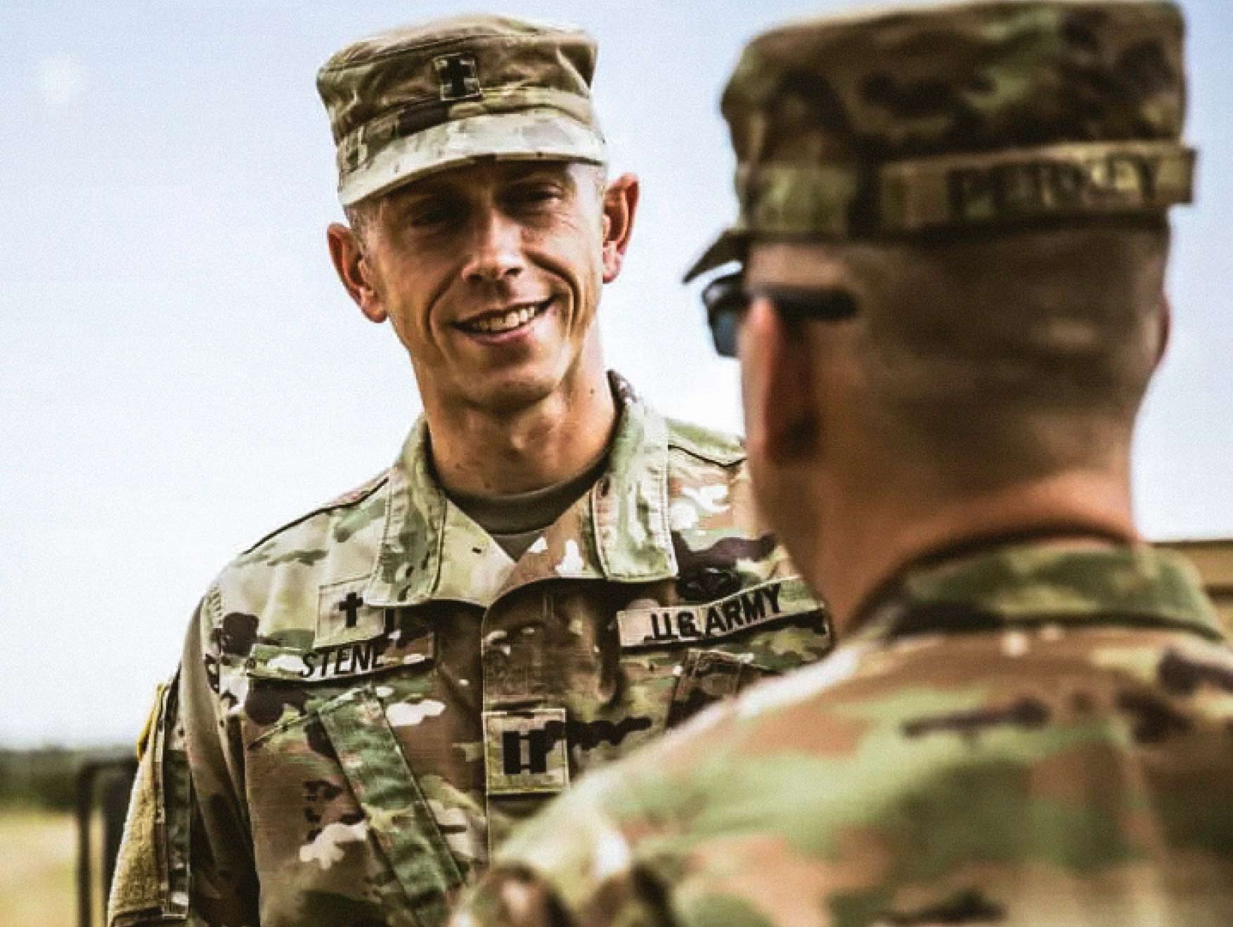 A male Field Chaplain talking to a Soldier outside during the day