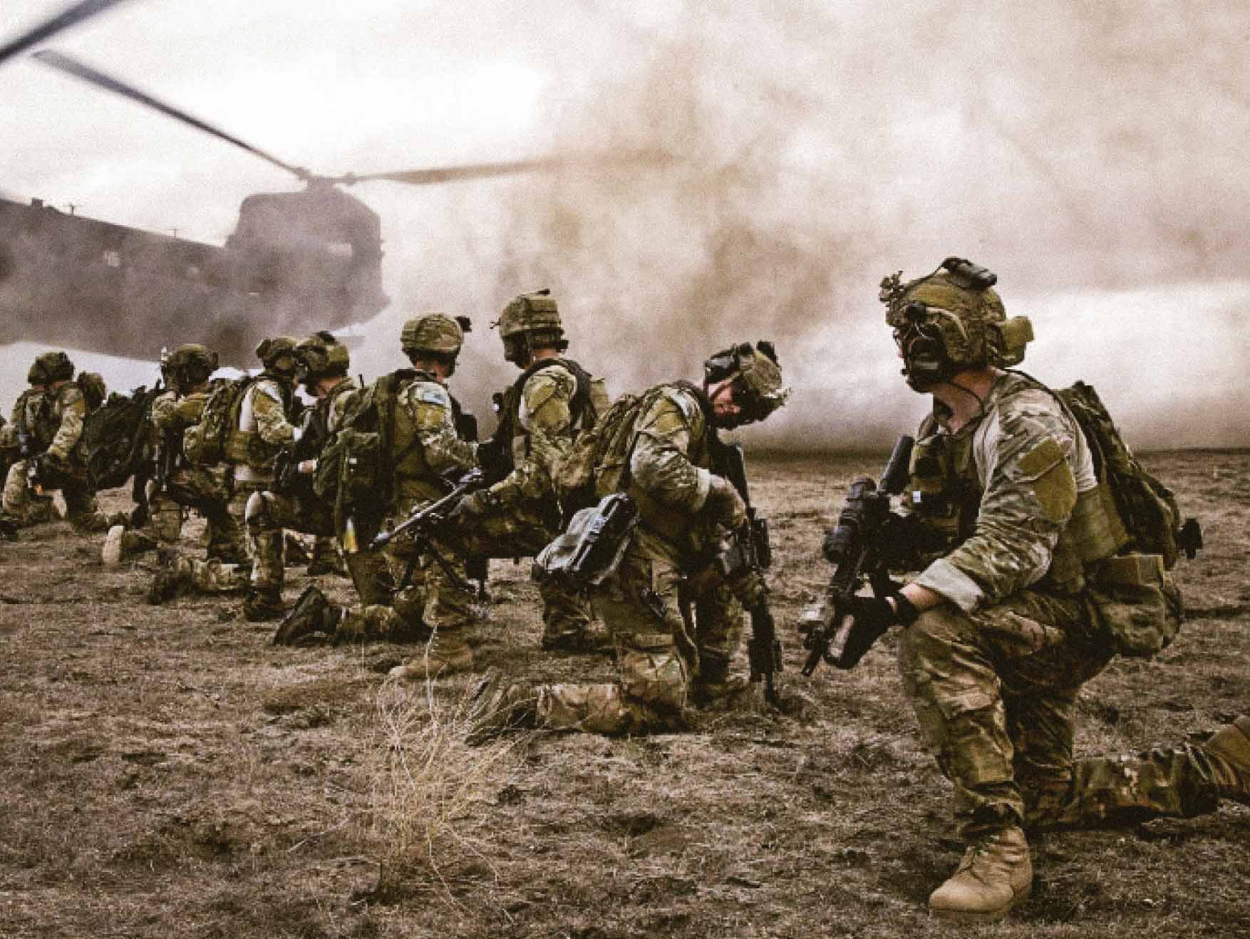 Soldier leading in the field, waiting for a Chinook helicopter to take off