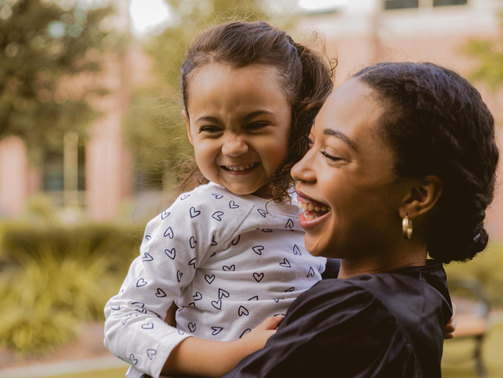 A smiling mother holding her young daughter