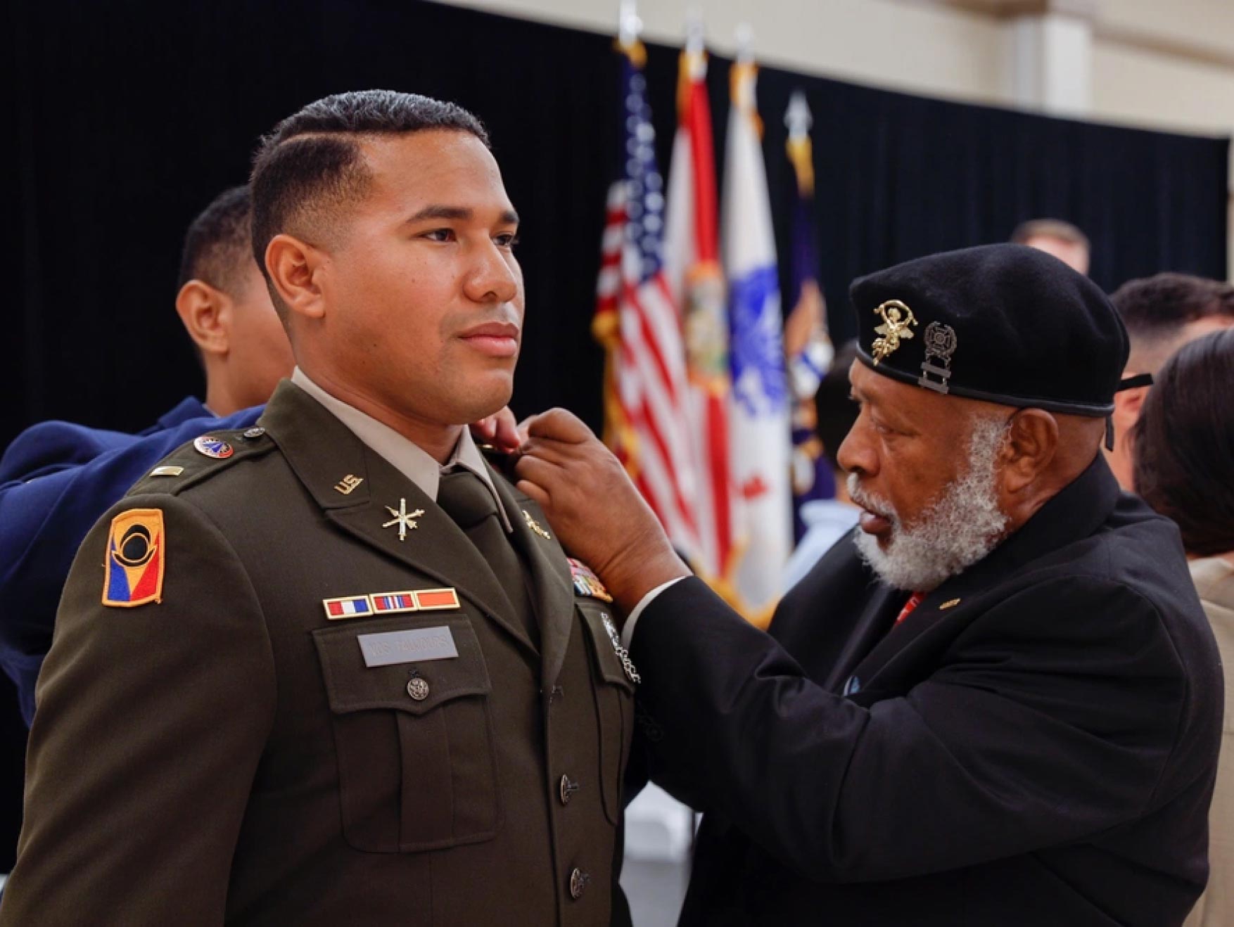 A male Officer Candidate is pinned by his father during an Officer Candidate School graduation ceremony. 