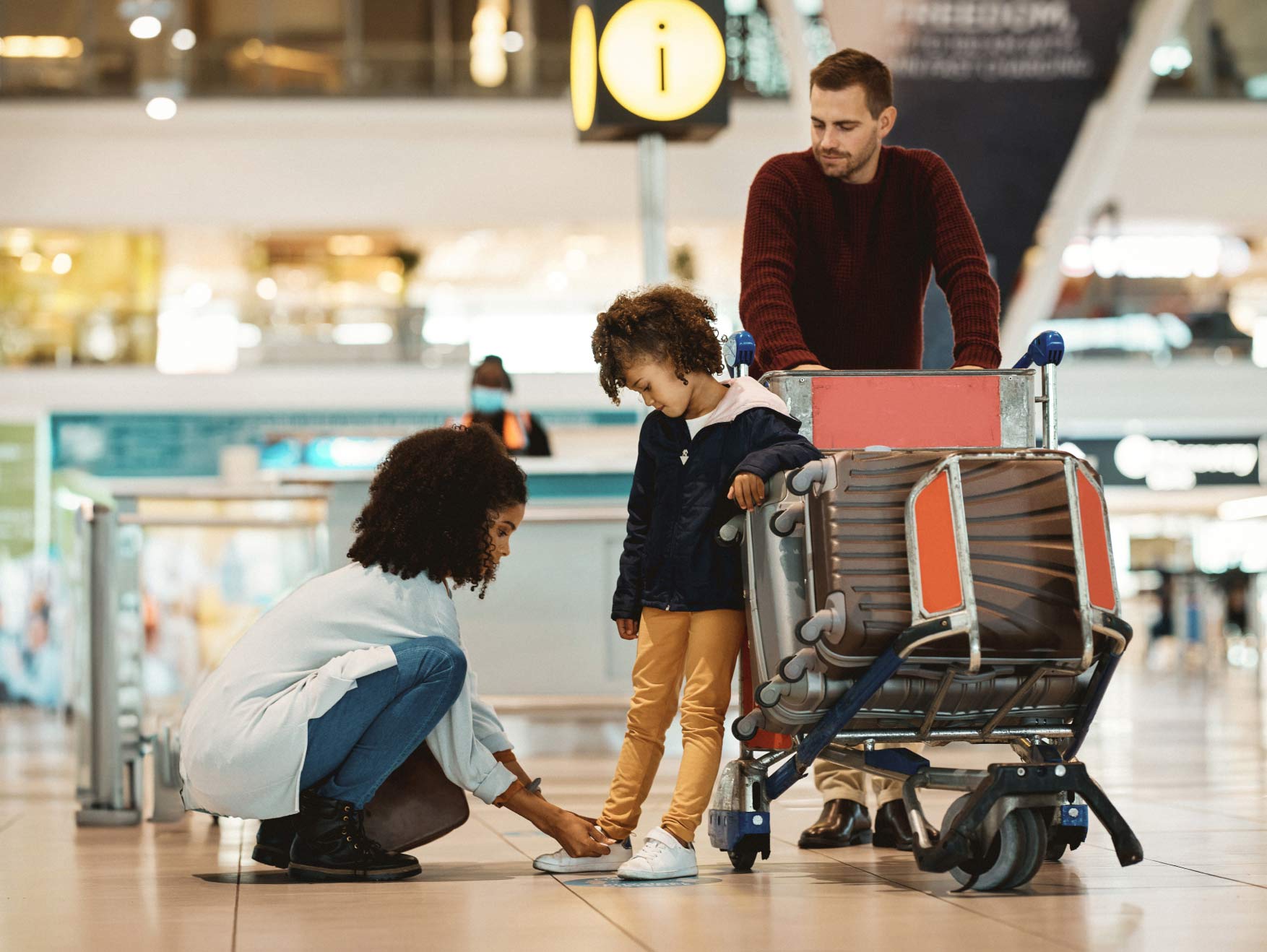 A mom tying her young child's shoes in an airport