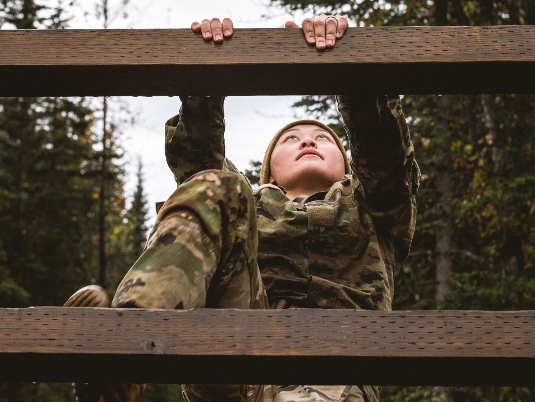 A Soldier climbing a wooden obstacle outside